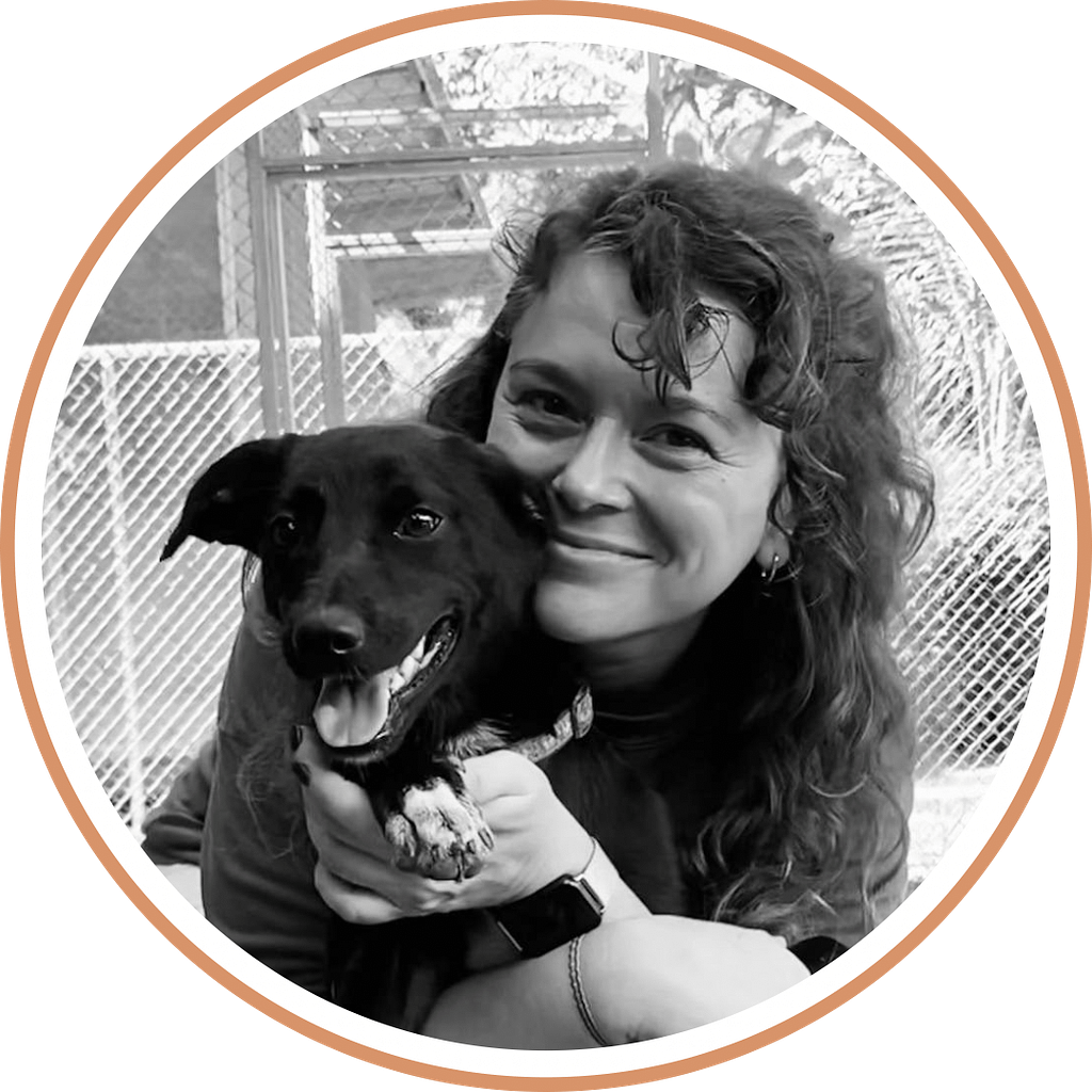 Volunteer with arms wrapped around black dog "Cherry" at the shelter.